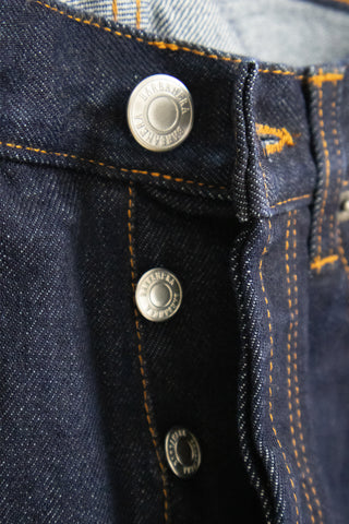 Close-up detail of the custom stud button on the Barbanera Bandito dark rinsed jeans, featuring a branded metal button with engraved logo on deep indigo denim fabric.