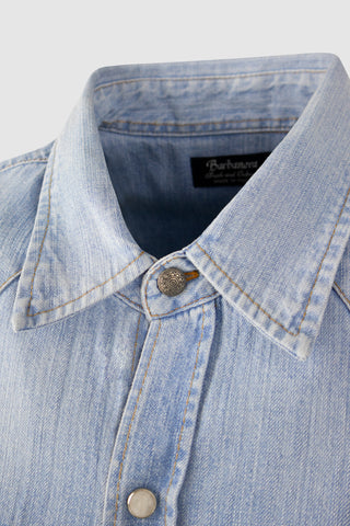 Close-up of the Barbanera Carlito light blue denim shirt showing the front button detail, featuring contrasting buttons and fine denim texture.