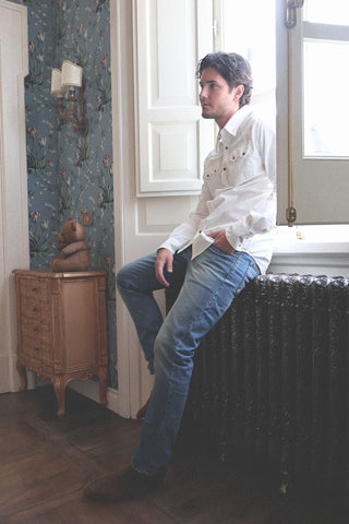 Lifestyle angled view of the Barbanera Carlito offwhite cotton shirt worn indoors, highlighting the western yoke, horn snap buttons, and slim fit.