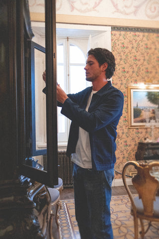 Side view lifestyle shot of the Barbanera Jericho dark rinsed overshirt, highlighting its tailored fit, sleeve details, and textured denim fabric in a casual indoor setting.